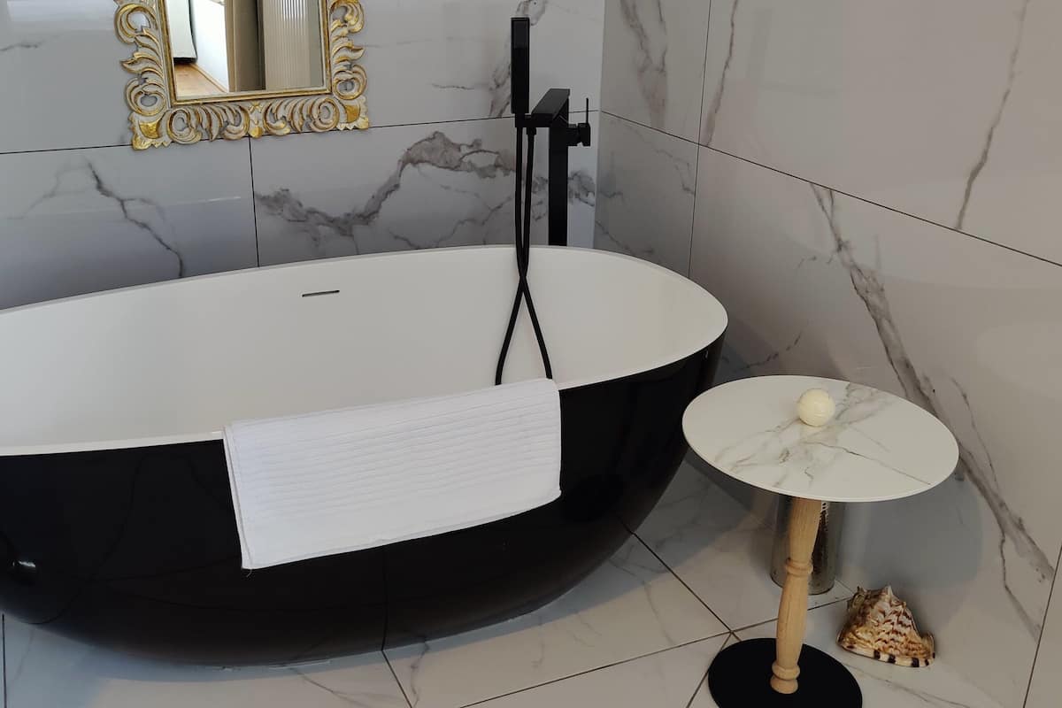 A modern bathroom with a freestanding bathtub, a marble-tiled floor, and a small round table with a marble top.