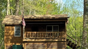 Una cabaña de madera con balcón, una bandera estadounidense y un panel de celosía.