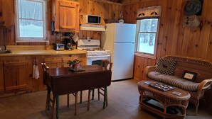 Una cocina acogedora de estilo cabaña, con paredes de madera, una mesa de comedor y un sofá de mimbre.