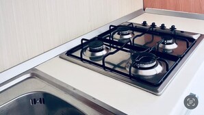 A kitchen with a gas stove, a sink, and wooden cabinets.