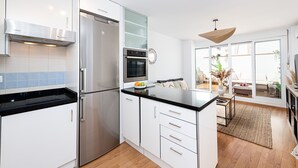 A modern kitchen with white cabinets, stainless steel appliances, and a black countertop.