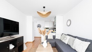 A modern living room with a grey sofa, a wooden coffee table, and a TV on a black stand.
