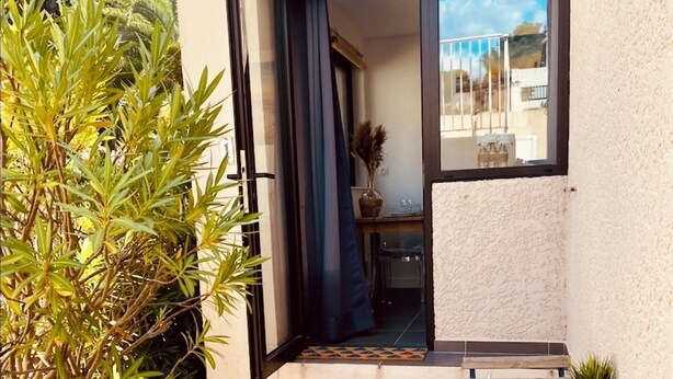 A patio with a wooden table, chairs, and a potted plant. - Appartement à Bandol Avec Piscine et Accès mer (Bandol)