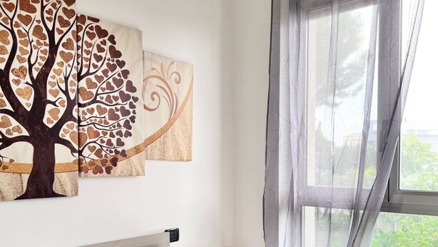 A bedroom with a bed, grey pillows, a bedside lamp, and a window with sheer curtains. - Apartment Capruzzi 2 (Bari)