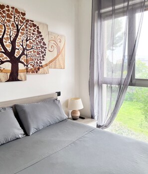 A bedroom with a bed, grey pillows, a bedside lamp, and a window with sheer curtains. - Apartment Capruzzi 2 (Bari)