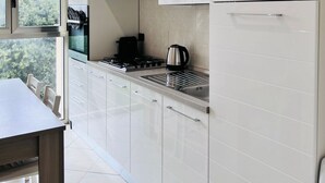A modern kitchen with white cabinets, a gas stove, and a kettle. - Apartment Capruzzi 2 (Bari)