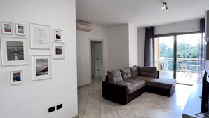 A modern living room with a sectional sofa, a flat-screen TV, and a balcony with outdoor furniture. - Apartment Capruzzi 2 (Bari)