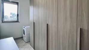 A modern kitchen with a built-in washing machine, a window, and a tiled floor. - Apartment Capruzzi 2 (Bari)