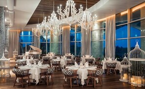 Enjoy meals in a beautifully set dining area with round tables, white tablecloths, and patterned runners.