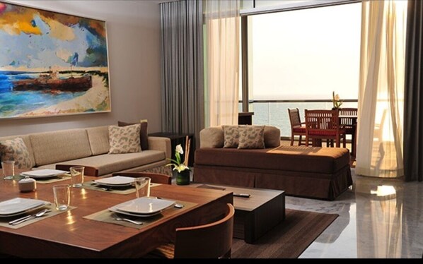 Relax in this stylish living room with a sofa set, dining table, and ocean views through the large window.