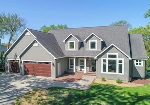 Une maison à deux étages avec un garage, une véranda et une pelouse bien entretenue.