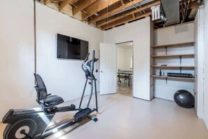 Une salle de sport à domicile équipée d’un vélo elliptique, d’un vélo d’appartement et d’un ballon lesté.