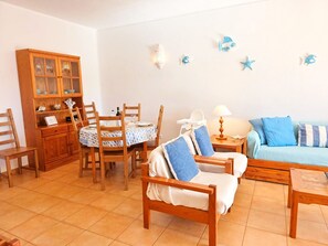 Una sala acogedora con una mesa de comedor, sillas de madera, un sofá y un aparador.