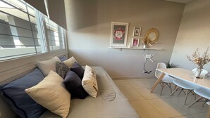 Un salon moderne avec un canapé, une table à manger et une planche à repasser fixée au mur.