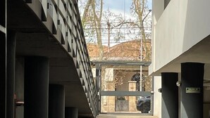 Une passerelle piétonne couverte, dotée d’une architecture moderne, qui mène à une entrée sécurisée par un portail.