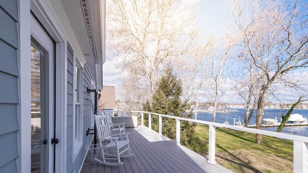 A wooden deck with white railings, a seating area with chairs, and a view of a body of water and trees. - Creek-Side Bliss: Unwind and Create Lasting Memories at Our Beautiful Retreat (Pasadena)