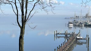 A dock extending into calm water with boats, a wooden walkway, and a tree. - Creek-Side Bliss: Unwind and Create Lasting Memories at Our Beautiful Retreat (Pasadena)