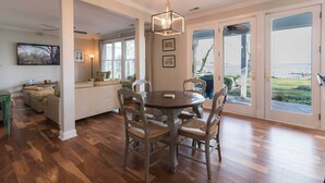 A dining area with a round table and chairs, a pendant light, and a view through large glass doors to an outdoor area. - Creek-Side Bliss: Unwind and Create Lasting Memories at Our Beautiful Retreat (Pasadena)