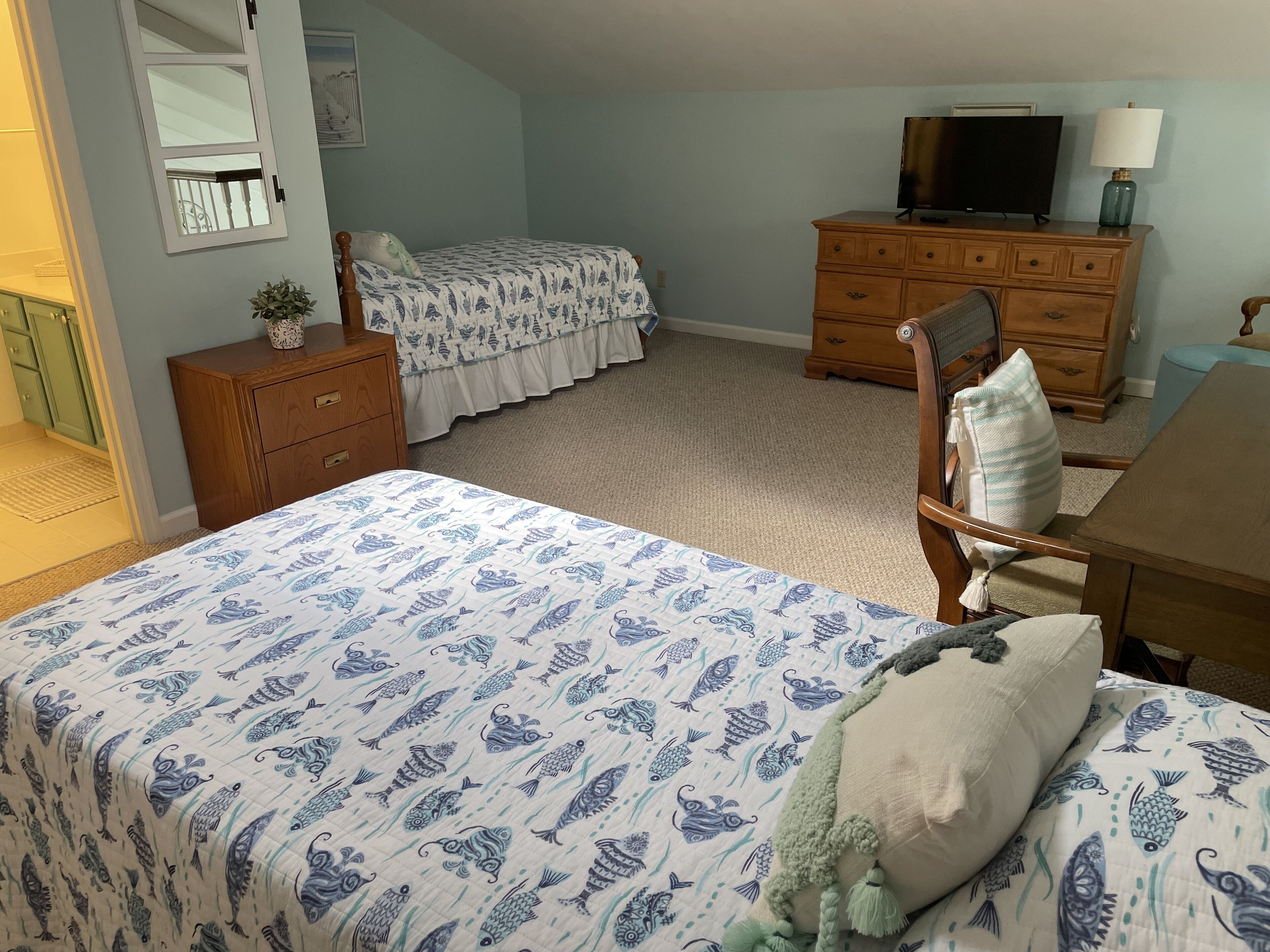A bedroom with a bed, a dresser, a chair, a television, and a lamp.