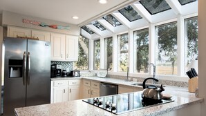 Una cucina moderna con frigorifero in acciaio inox, piano cottura integrato e un'ampia finestra vista giardino.