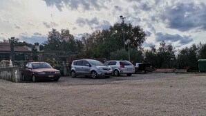 Ein Kiesparkplatz mit drei parkenden Autos.