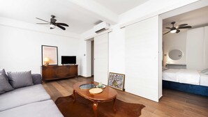 Una sala de estar moderna con un sofá, una mesa de centro, un televisor y un ventilador de techo.