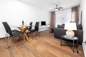 Relax in this stylish living space with a dining area, featuring a glass-top table and comfortable seating for four.