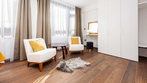 Una habitación de hotel moderna con un sofá blanco, una mesita redonda y una alfombra de piel sobre el suelo de madera.