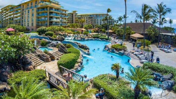 A resort with a large pool area, multiple swimming pools, and a building with balconies.