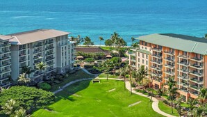 A hotel with multiple floors, a well-maintained lawn, and a view of the ocean.