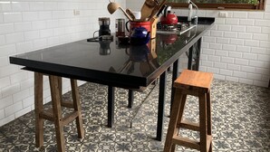 A kitchen with a black countertop, wooden stools, and a window with a view of greenery. - Awesome View, Valparaiso Terrace (Valparaíso)