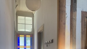 A hallway with wooden flooring, a stained glass door, and a hanging light fixture. - Awesome View, Valparaiso Terrace (Valparaíso)