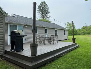 Eine Terrasse mit Gartenmöbeln, einem Grill und Lichterketten vor einem Haus.