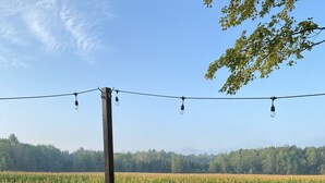 Una terrazza con tavolo e sedie, affacciata su un campo di mais.