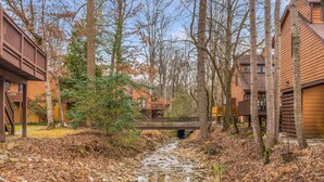 Un rustico chalet con una veranda in legno e un piccolo ponte su un ruscello.