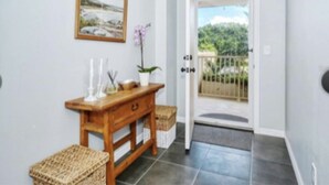 A hallway with a wooden console table, wicker baskets, and a framed picture on the wall. - Longboat Key Condo with a View (Longboat Key)