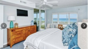 A bedroom with a bed, a wooden dresser, a ceiling fan, a TV, and a view of the beach. - Longboat Key Condo with a View (Longboat Key)