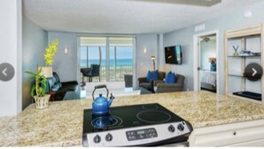 A modern kitchen with a gas stove, a dining area with a view, and a living room with a sofa and a TV. - Longboat Key Condo with a View (Longboat Key)