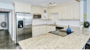 A modern kitchen with white cabinets, stainless steel appliances, and a granite countertop. - Longboat Key Condo with a View (Longboat Key)