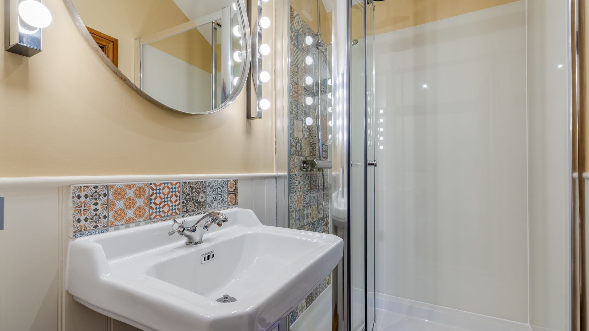 A bathroom with a white sink, a mirror, and a shower area with glass doors.