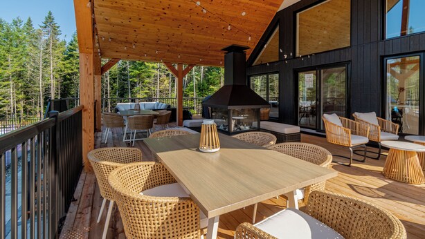 A wooden deck with wicker furniture, a large table, and a chimney. - Hôtel à la maison - Villa Skáli (Shannon)