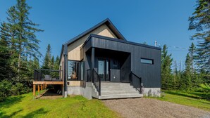 A modern two-story house with a dark exterior, a visible number '190', and a wooden deck with outdoor seating. - Hôtel à la maison - Villa Skáli (Shannon)