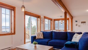 A spacious living room with a blue sofa, wooden coffee table, and large windows.