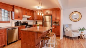A modern kitchen with wooden cabinets, stainless steel appliances, and a central island with stools.