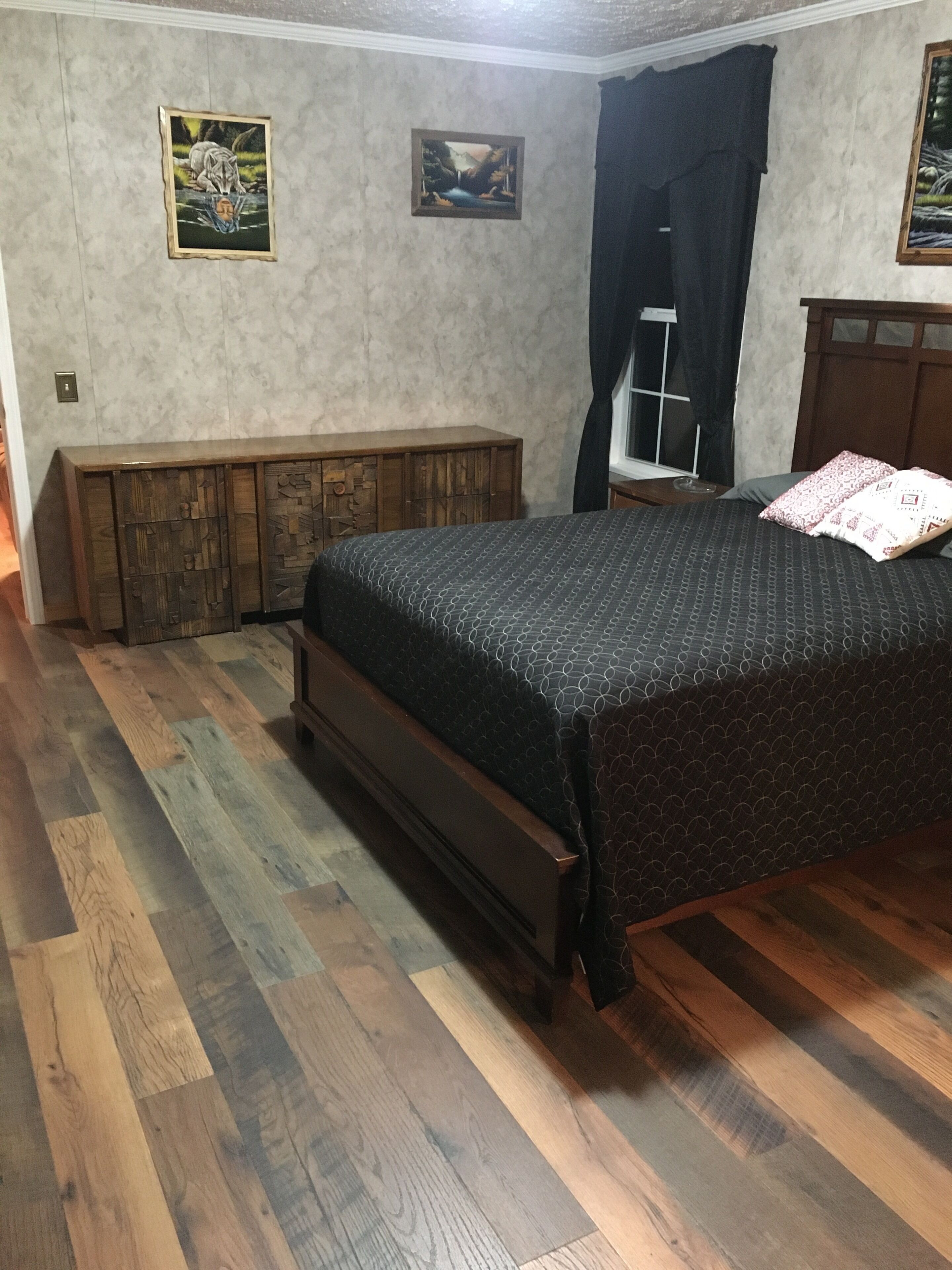 A bedroom with a wooden bed, a bench, and two framed pictures on the wall.