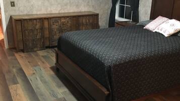 A bedroom with a wooden bed, a bench, and two framed pictures on the wall.