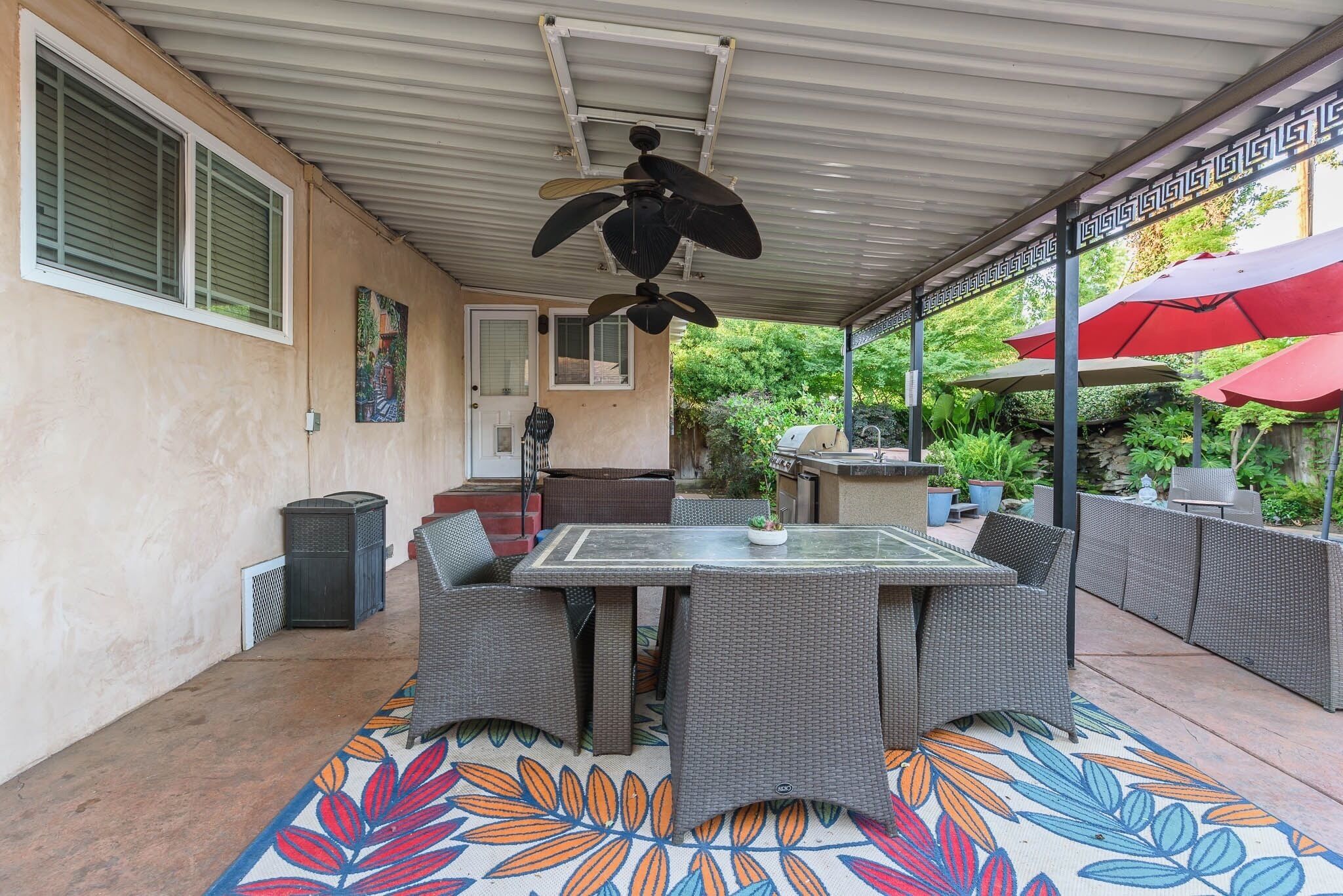 A covered patio area with a dining table, chairs, and a ceiling fan.