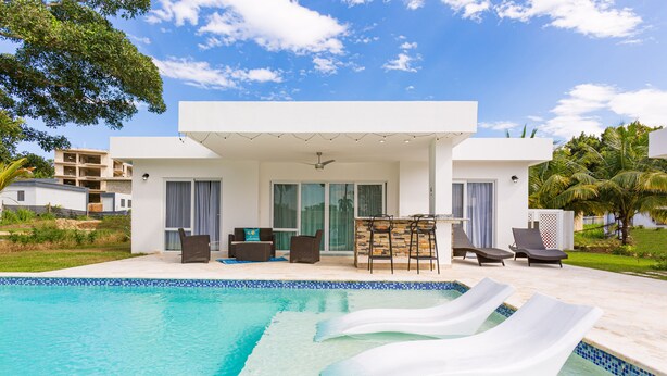 Et moderne hus med swimmingpool, udendørs siddepladser og en overdækket terrasse.