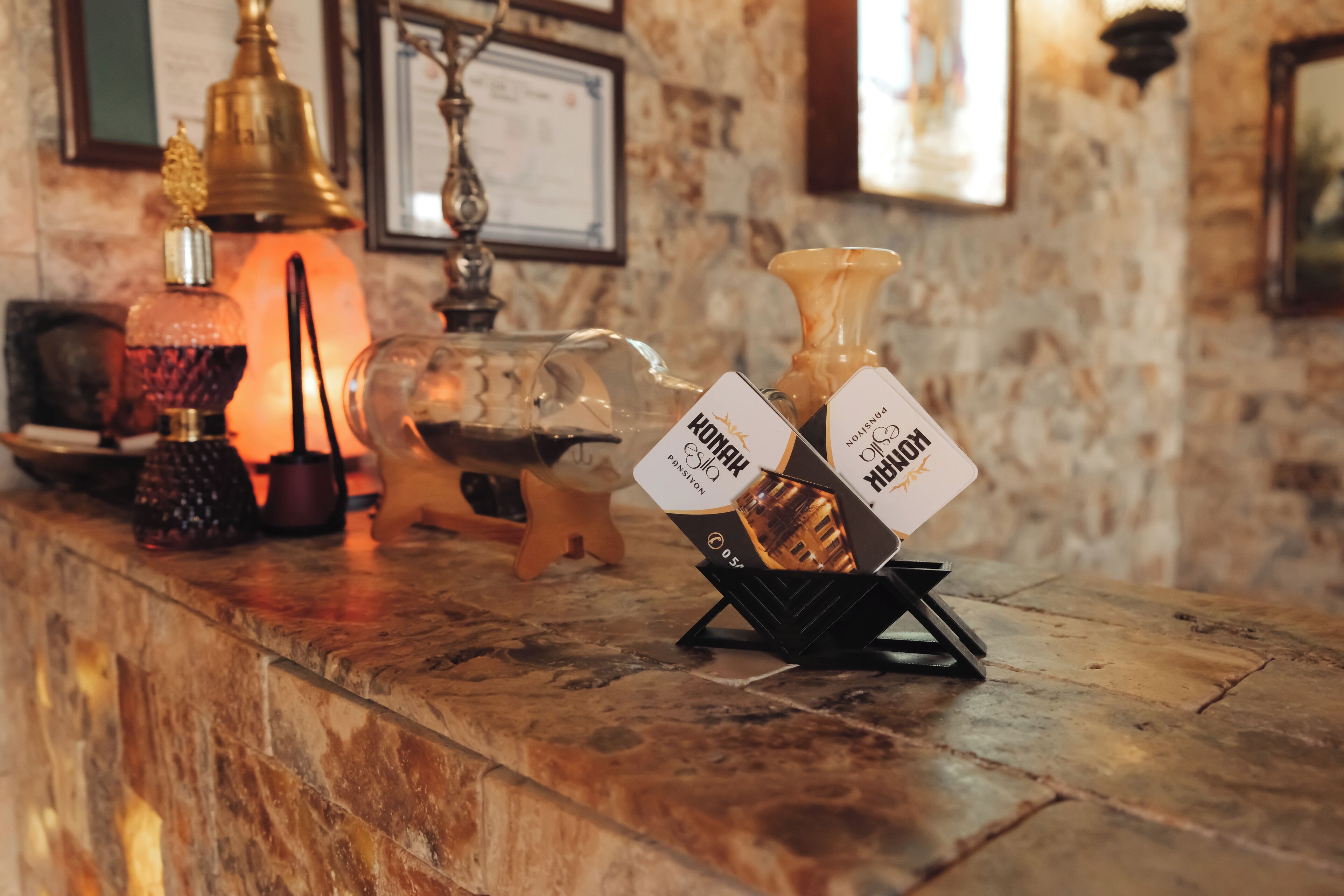 A bar area with a marble countertop, a brass bell, a lit candle, and a wine bottle rack with two bottles labeled "HONEY" and "ROSE."