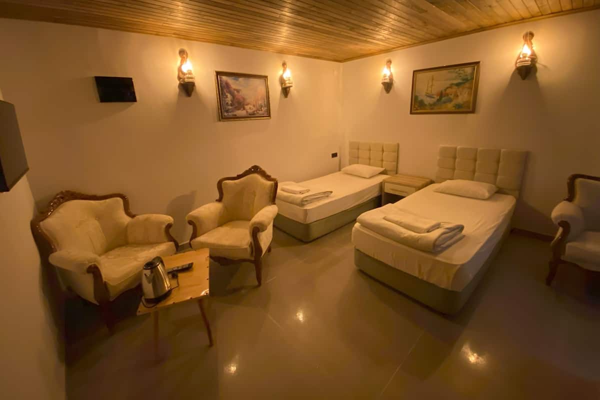 A hotel room with two single beds, a sofa, a chair, and a small table.